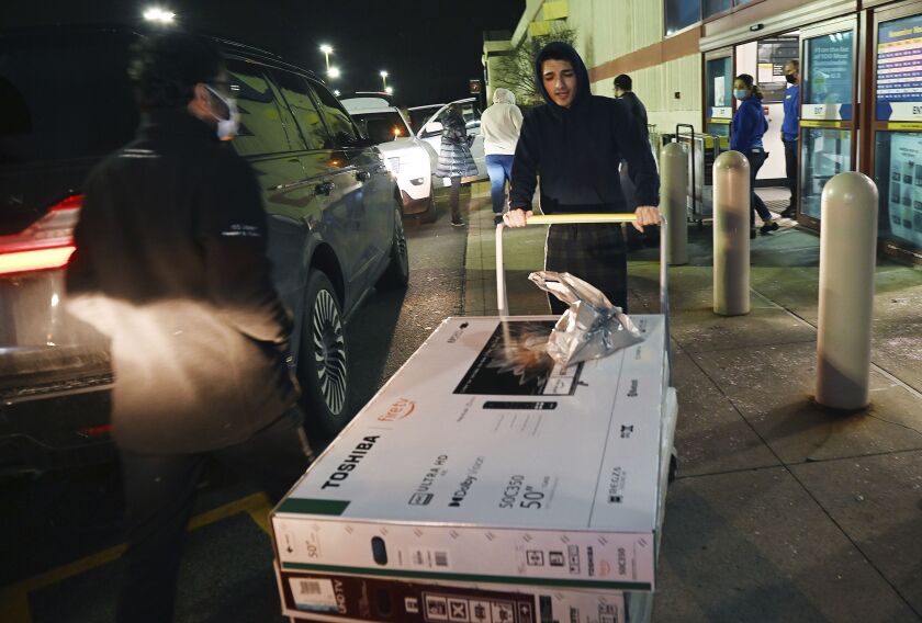 Sebastian Semma, 20, of Novi, Mich., carries his new 50” flat screen televisions to his truck after purchasing them at Best Buy on Friday, Nov. 26, 2021.