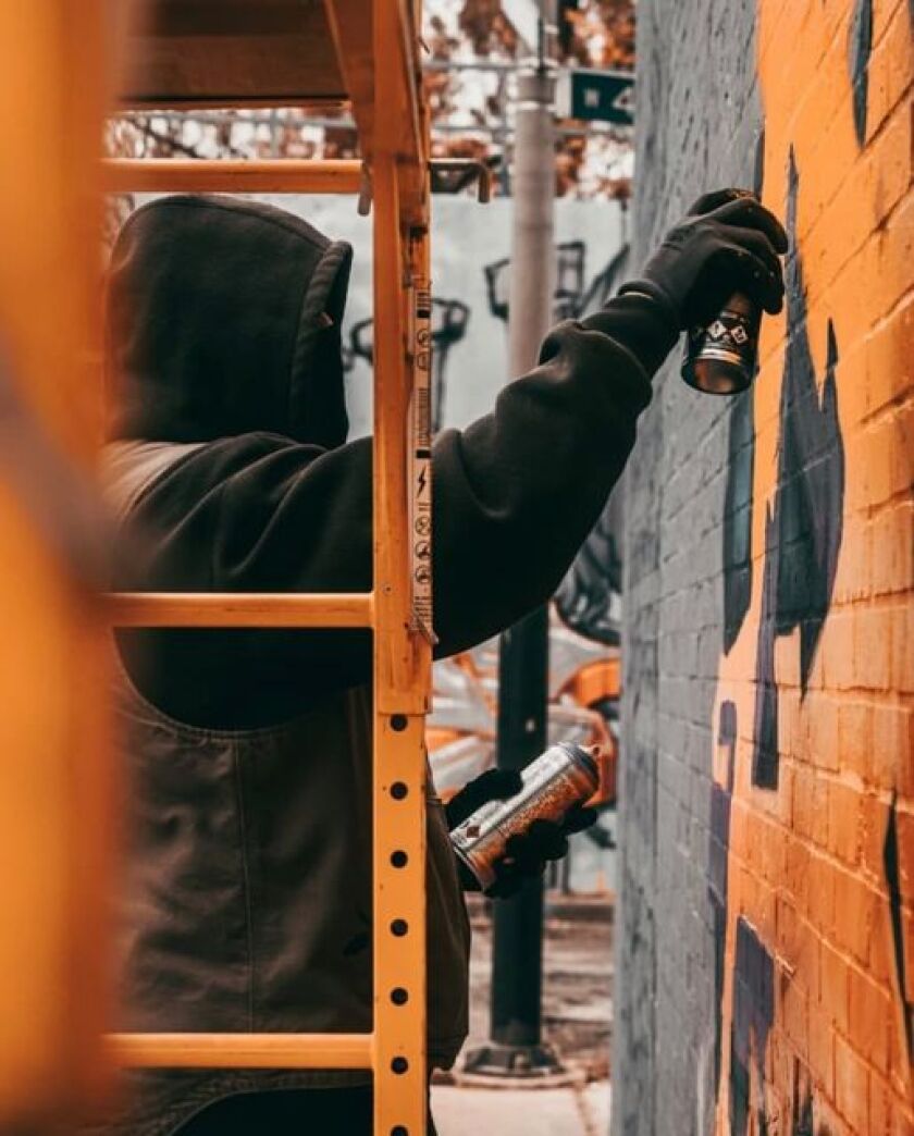 The artist who passes by Doer, shown painting a wall in 2021.