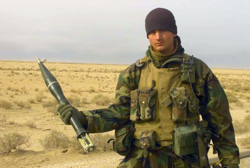 Then-Marine Corp. Tyson Manker displays an anti-tank grenade found in a weapons cache in March 2003 near Az Zubayr, Iraq.