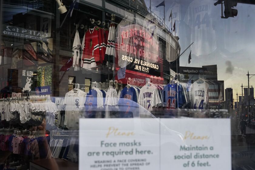 The Wrigley Field marquee is reflected in the window of the Sports World apparel store.