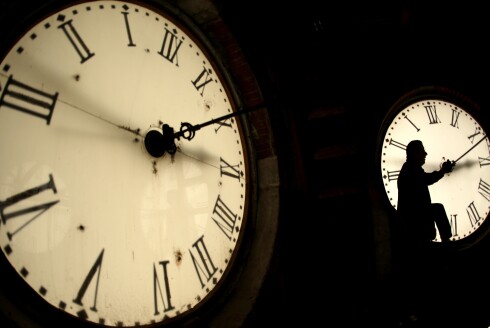 A custodian inspects a clock face before changing the time on a 100-year-old clock in Kansas.