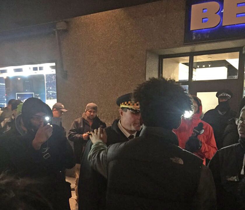 Protesters, police shake hands outside the John Hancock Center late Friday night. | Mitchell Armentrout/For the Sun-Times