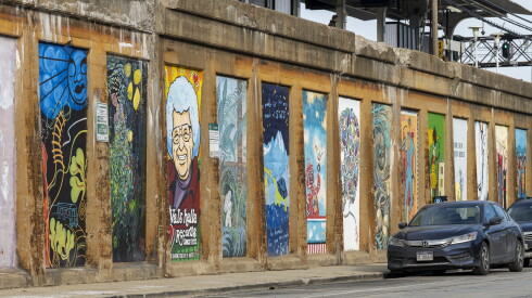 An assortment of murals adorns the side of a Green Line retaining wall in Oak Park.