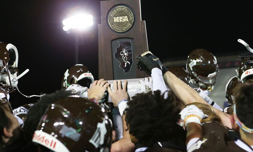 Joliet Catholic’s players celebrate after receiving the Class 4A state championship trophy.