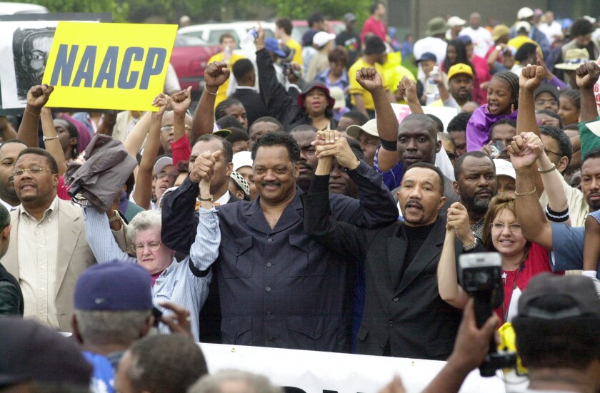 Jesse Jackson and then-NAACP president Kweisi Mfume, center, join hands as they march in Greenville, SC, on May 17, 2003. They were rallying to protest the Greenville County council's decision not to recognize a Martin Luther King Holiday.