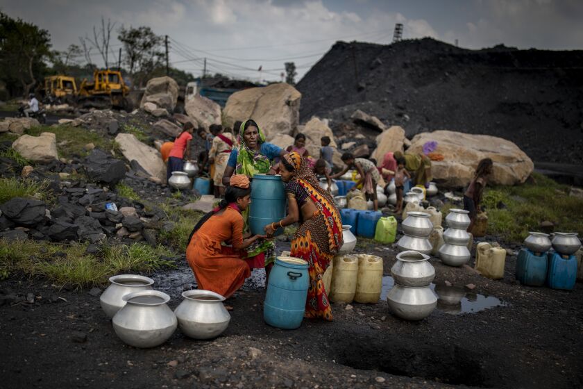 Members of coal workers’ community fetch drinking water from a pipe at a coal depot near an open-caste mine in Dhanbad.