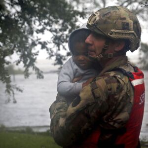 Rescue team member Sgt. Nick Muhar, from the North Carolina National Guard 1/120th battalion, evacuates a young child as the rising floodwaters from Hurricane Florence threatens his home in New Bern, N.C., on Friday, Sept. 14, 2018. (AP Photo/Chris Seward