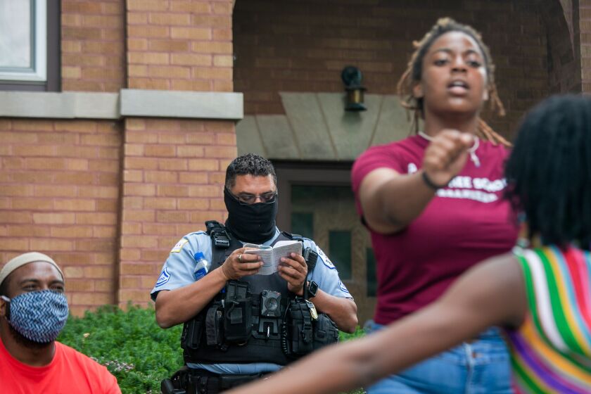 A police officer reads a handbook while guarding Chicago Board of Education president Miguel del Valle’s home in Belmont Cragin as youth activists hold a teach-in June 24, 2020, to demand an end to police presence in schools.
