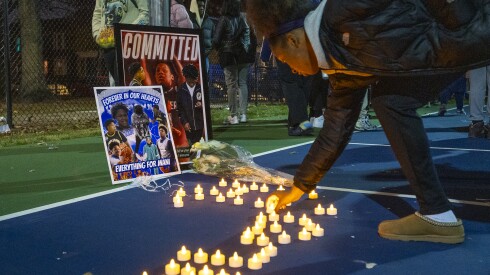 A young woman adjusts a candle in a small vigil for Armani Floyd in a basketball court outside Gary Comer College Prep Middle School in the Grand Crossing neighborhood, Monday, Nov. 24, 2025. Floyd was shot and killed Friday night in The Loop near the Chicago Theatre. | Tyler Pasciak LaRiviere/Sun-Times