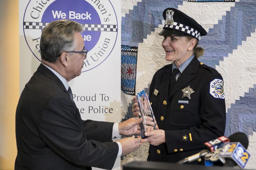 Hiram Grau, a board member for the Chicago Police Memorial Foundation, presents Officer Therese Puchalski with an award for assisting in the birth of twin girls on Nov. 1 at the Red Line’s Roosevelt Road station during a ceremony at the Chicago Patrolmen’