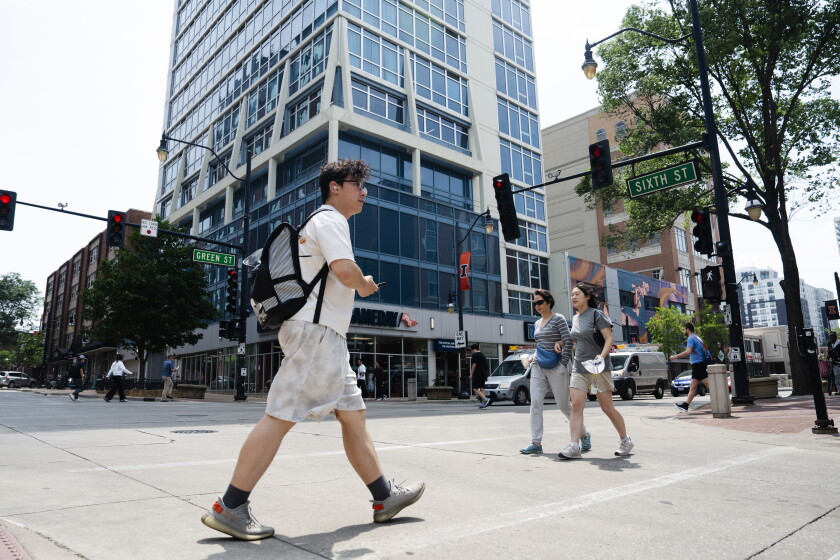 People walk around Green Street, which is lined with restaurants, near the University of Illinois Urbana-Champaign, Tuesday, June 3, 2025.