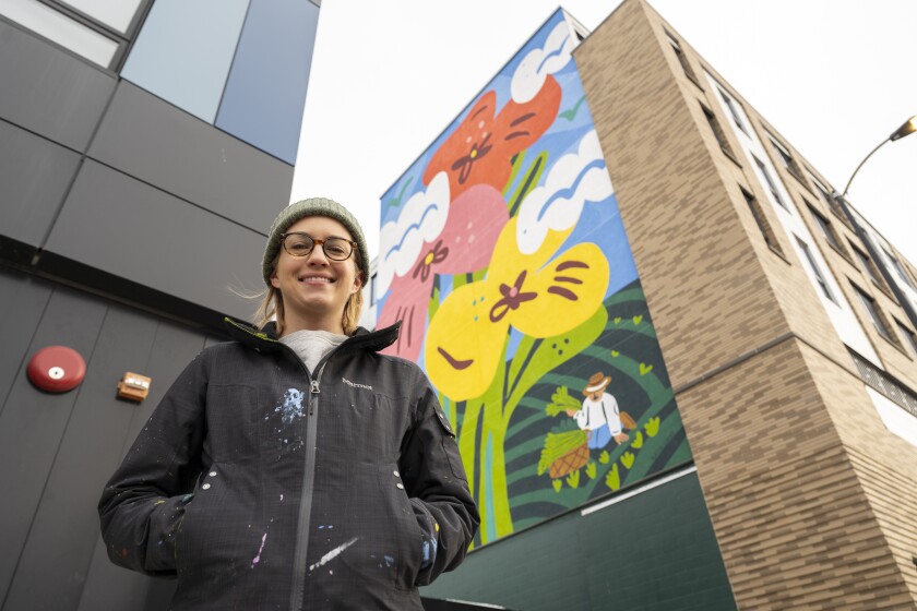 هنرمند کیتی لوکس در کنار بزرگترین پروژه دیوارنگاری خود تا به امروز در یک ساختمان لینکلن اسکوئر ایستاده است.