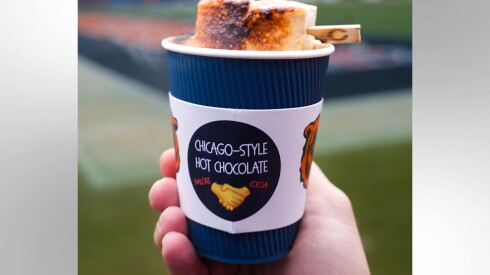 A hand holding up a cup of Chicago-style hot chocolate, with Malört and Amaretto.