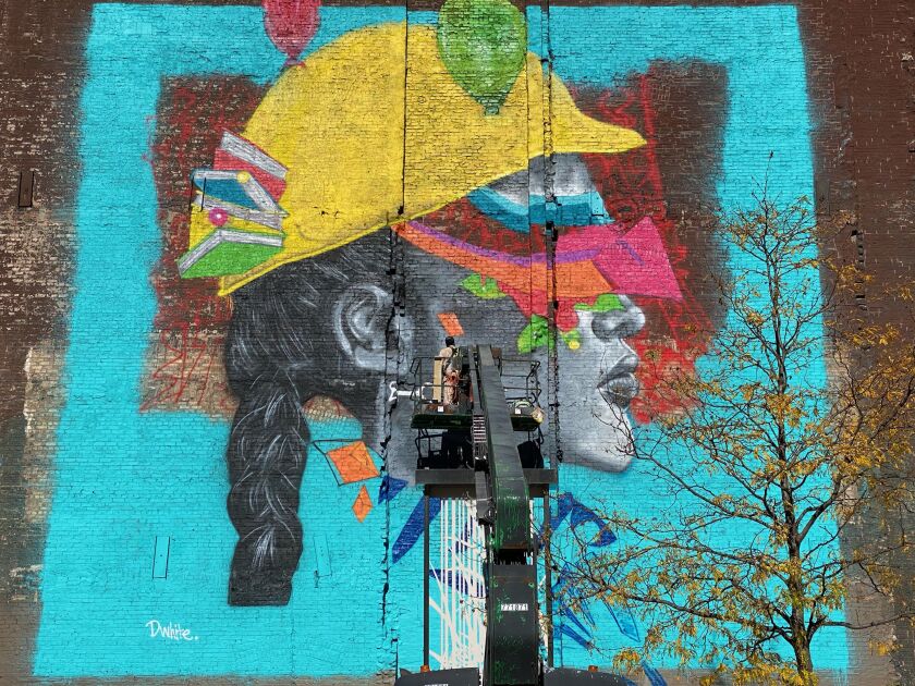 Dwight White II works on a mural on Ida B. Wells Drive this fall.