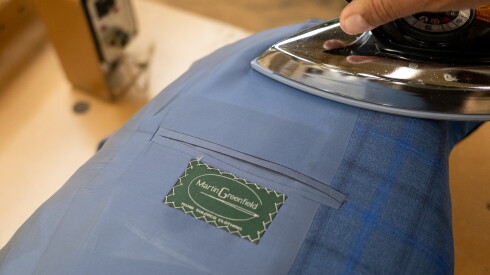 An employee irons a suit jacket in the factory at Martin Greenfield Clothiers in Brooklyn, New York, on Aug. 11, 2026.