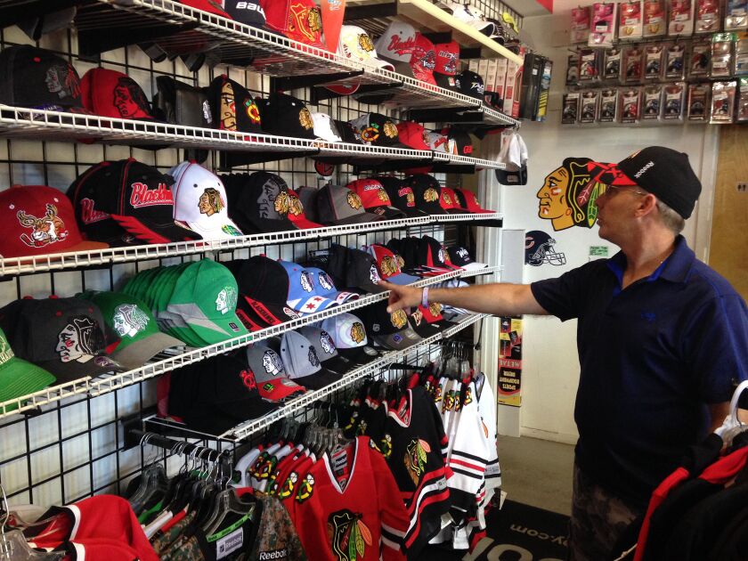 <small><strong>Gunzos employee Mike Uczen shows off some of the store’s Hawks gear. Anything that said “2015 Stanley Champions” is long gone, but more obviously is on the way. | Mitch Dudek/Sun-Times</strong></small>