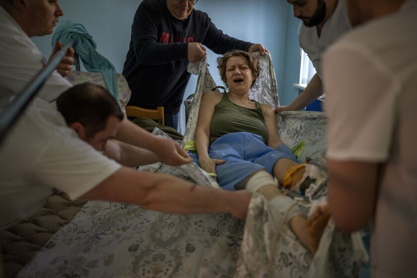 Olena Viter, 45, is moved to a stretcher before being taken to undergo more surgery at a public hospital in Kyiv, Ukraine. The explosion that took her left leg also killed her son Ivan, a 14-year-old , budding musician already playing in a small orchestra. Her husband Volodymyr buried him and another boy killed in the same blast under a guelder-rose bush in their garden.