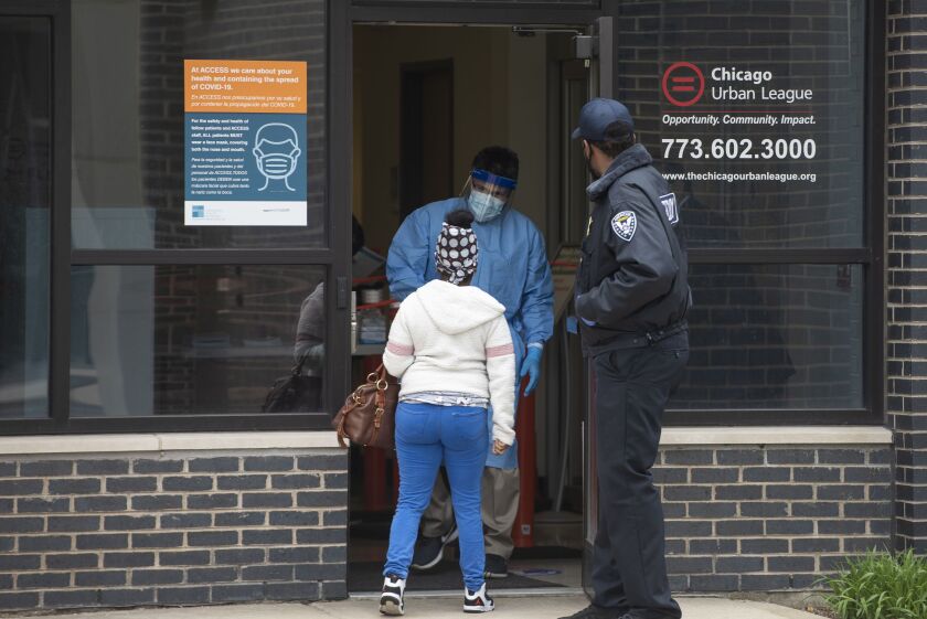 A woman talks with a medical professional at the entrance of Access Family Health Center in Englewood who started providing coronavirus testing to the community, Monday, May 4, 2020. | Tyler LaRiviere/Sun-Times