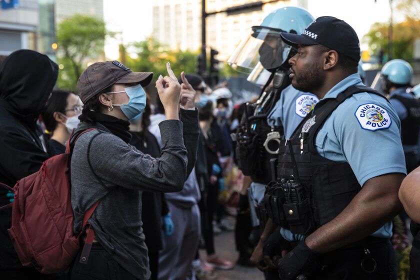 A woman gives a Chicago police officer the middle finger during a protest at East 53rd Street and South Lake Park Avenue in Hyde Park on the third day of protests in Chicago over the death of George Floyd, Sunday evening, May 31, 2020. Floyd died in police custody on Memorial Day in Minneapolis.