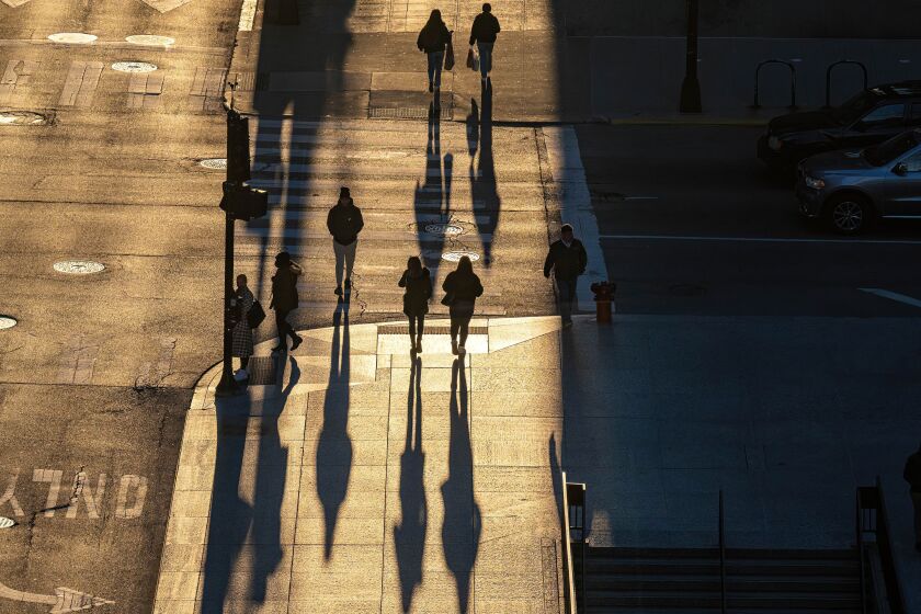 Pedestrians walk along the sidewalk near West Washington Street near Daley Plaza in the Loop, Tuesday, March 28.