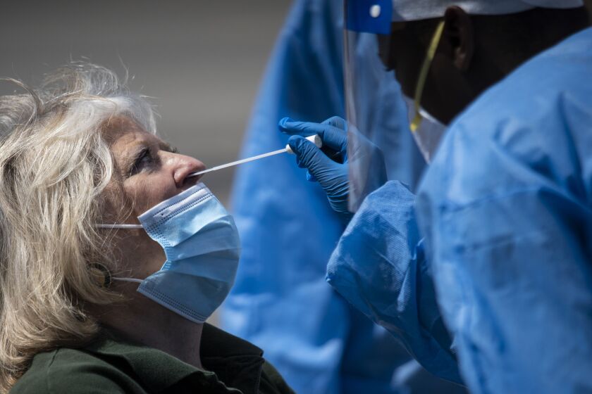 Phlebotomist Crystal Bovan, with Simple Laboratories, collects a nasopharyngeal swab sample to test for the coronavirus for Harwood Heights Mayor Arlene Jezierny at the lab’s drive-thru testing site in the parking lot of St. Rosalie Catholic Parish in Harwood Heights, Friday, May 1, 2020.
