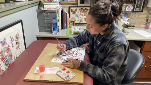 Danni Nievera copies a classic tattoo design to be used as a reference for customers.