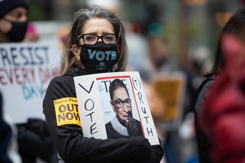 Ruth Novak holds a sign with the late Supreme Court Justice Ruth Bader Ginsburg’s picture during the Women’s March, which aims to rally voters, at Federal Plaza in the Loop, Saturday morning, Oct. 17, 2020.
