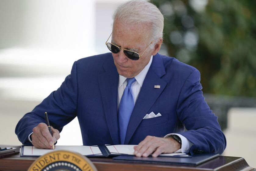 President Joe Biden signs two bills aimed at combating fraud in the COVID-19 small business relief programs at the White House on Aug. 5, 2022.