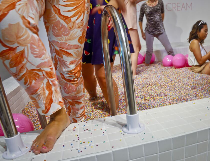 Visitors walk into a large pool filled with faux confetti-colored sprinkles, the biggest attraction of ice cream-themed works of art previewed at the Museum of Ice Cream, Thursday July 28, 2016, in New York. | AP Photo/Bebeto Matthews
