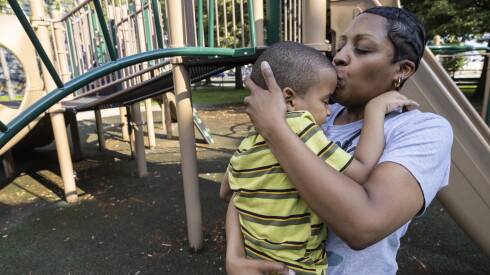 Tiffany kisses her son on the forehead at the playground of his school.