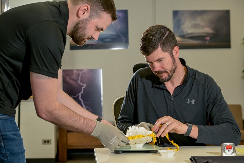 PHD Student Logan Bundy and Professor Meteorology Victor Gensini at Northern Illinois University measure and weigh the new Illinois State record hail stone, that was collected from the Kankakee area during TuesdayÕs storm, in their lab in DeKalb on Thursday, March 12, 2026. The stone measures in at over 6 inches and over 1 pound in weight. | Mark Black / For the Sun-Times