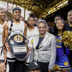 Simeon’s Aneesah Morrow (24) holds the trophy and stands with her team, coach Johnny Davenport and Mayor Lori Lightfoot after winning the city championship against Kenwood.