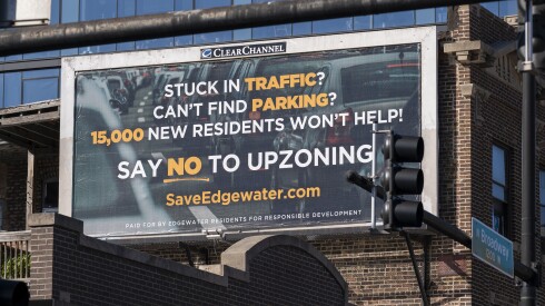 A billboard against a brick building saying, "Stuck in traffic? Can't find parking? 15,000 new residents won't help! Say no to upzoning"