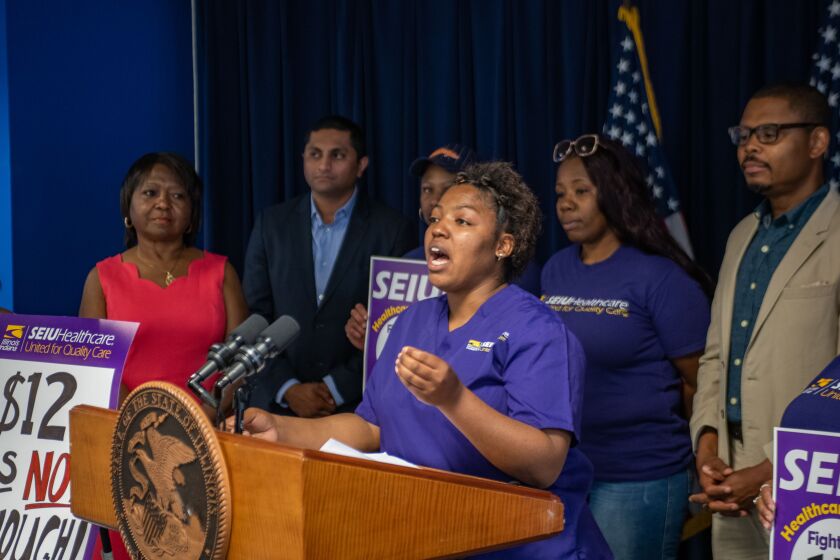 Tichina Haywood, center, speaks at a press conference about raising the minimum wage in June 2018. | Provided photo.