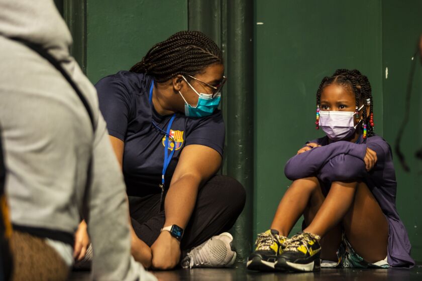 Councilor Kierra Towns, 25, who lost her mother as a child, chats with Mia as other children play during Hearts to Art summer camp on July 11.