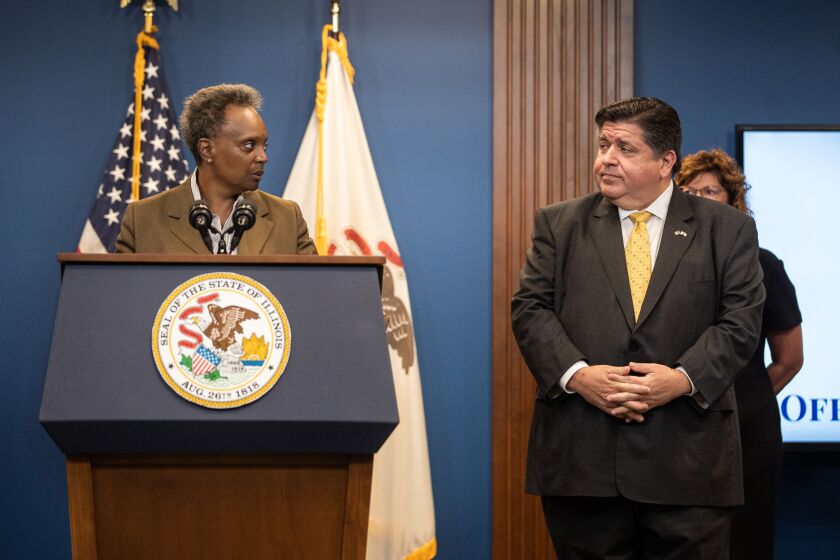 Gov. J.B. Pritzker and Chicago Mayor Lori Lightfoot look at each other during a press conference in the Greektown neighborhood, where Pritzker announced that he signed a disaster proclamation and called on the Illinois National Guard to support over 500 migrants who were sent by Texas Gov. Greg Abbott to Illinois, Wednesday, Sept. 14.