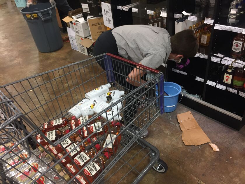 Workers clean up the shattered glass left by looters who broke into the Binny’s Beverage Depot in Lincoln Park overnight.