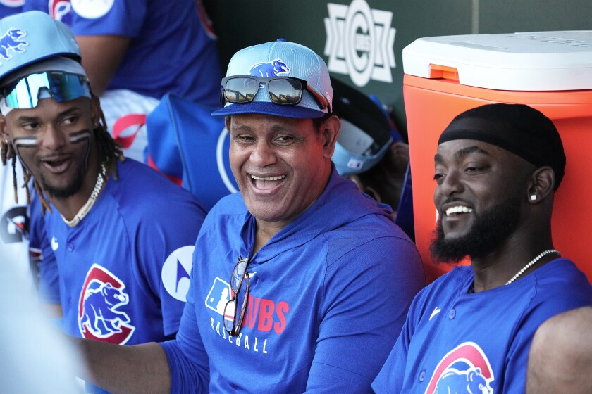 Cubs legend Sammy Sosa (center) shares a laugh with outfielder Kevin Alcántara (left) and utility player Vidal Bruján in the dugout during a spring training game at Sloan Park in Mesa, Arizona, on Feb. 25, 2025.