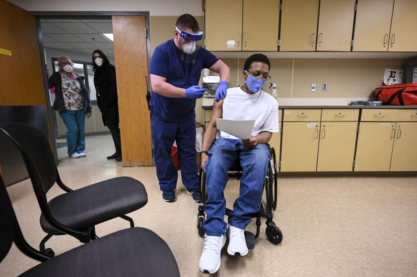 Kelly Markham, a registered nurse supervisor at Minnesota’s Faribault Prison, administers the state’s first COVID-19 vaccination to a medically vulnerable inmate, Edward Anderson, in January.