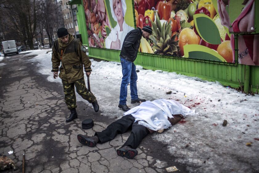 A civilian and an separatist soldier look at the body of a man after shell hit a residential area, killing two civilians in Donetsk’s Kyibishevsky district, on January 29, 2015. MANU BRABO/AFP/Getty Images
