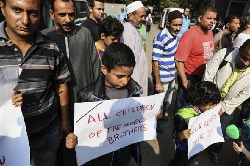 Egyptian boys hold posters to share sorrow outside Zeinhom morgue, where bodies of Russian plane crash victims were kept on Sunday, in Cairo, Egypt. | Mohammed El Raai/AP