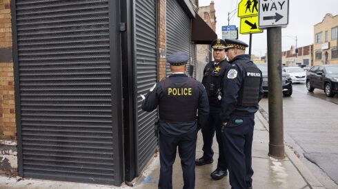 Police officers look at the bullet holes on the security curtains at Studio 1258, where 15 people were shot during a party at the corner of South Pulaski Road and West 13th Avenue, Sunday, Oct. 29, 2023.