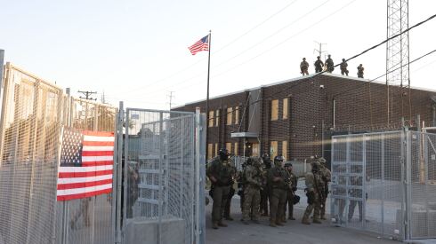 ICE agents stand guard inside the gates of the Broadview facility after a confrontation with protesters.