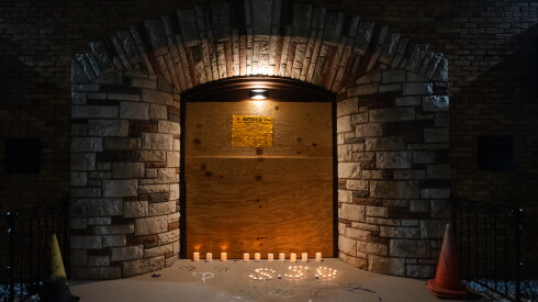 Candles are lit outside the boarded-up entrance of South Chicago Chapel in South Deering during a vigil for people looking for answers about their loved ones’ remains, Sunday, Aug. 30, 2026.