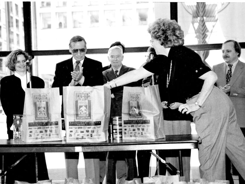 Mary Cameron Frey (right) adds her contribution to Operation Brown Bag at a 1994 Daley Plaza kickoff event for the annual food drive. Behind the table are (from left) fellow Chicago Sun-Times columnists Ginny Holbert, Irv Kupcinet, Ray Coffey and Lon Grah