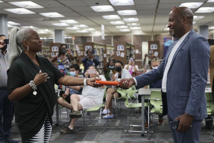 Retiring Principal Dr. Joyce Kenner hands off a baton to Assistant Principal Rickey Harris during a vote Wednesday confirming Harris as the new leader at Whitney Young Magnet High School on the Near West Side.
