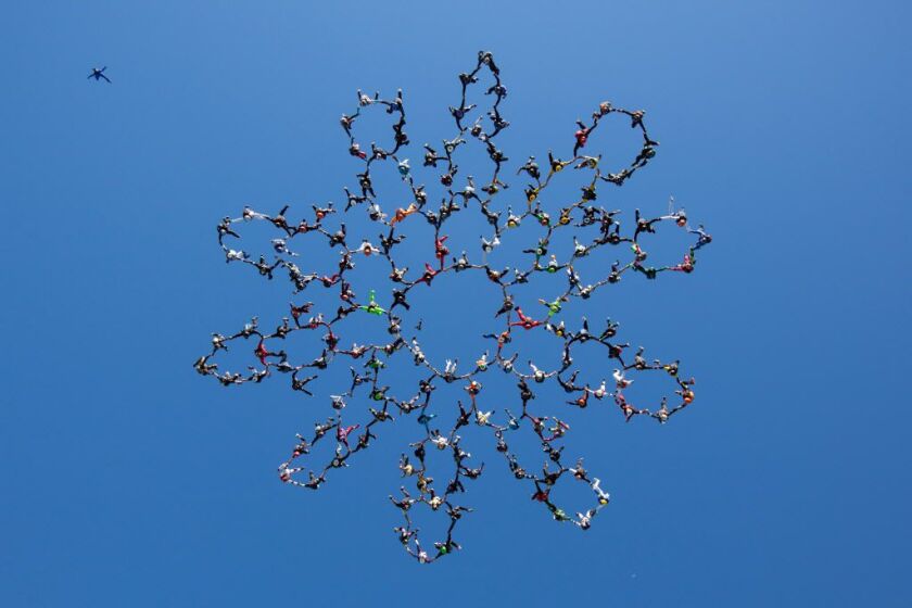 In this photo provided by Jason Peters, members of an international team of skydivers join hands flying head-down to build their world record skydiving formation Friday, July 31, 2014, over Ottawa, Ill. It took the team 13 attempts to to build the formati