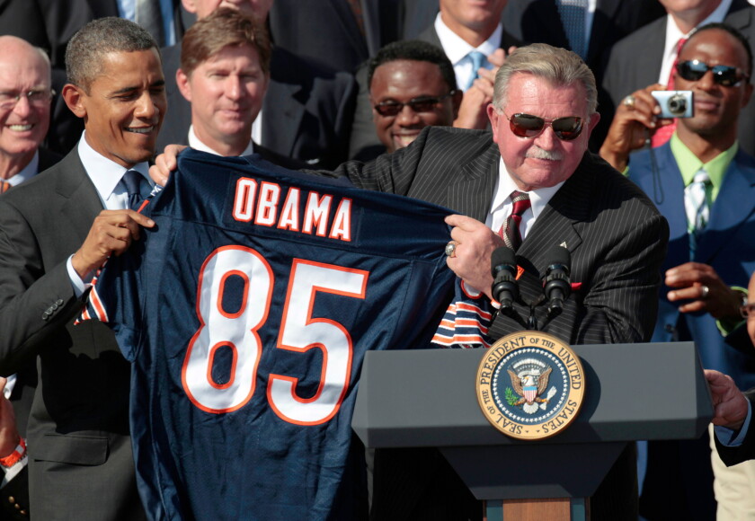 President Barack Obama is presented with a team jersey by former Bears' head coach Mike Ditka as he stands with the 1985 Super Bowl XX Champions Chicago Bears NFL football team during a ceremony at the White House Oct. 7, 2011.