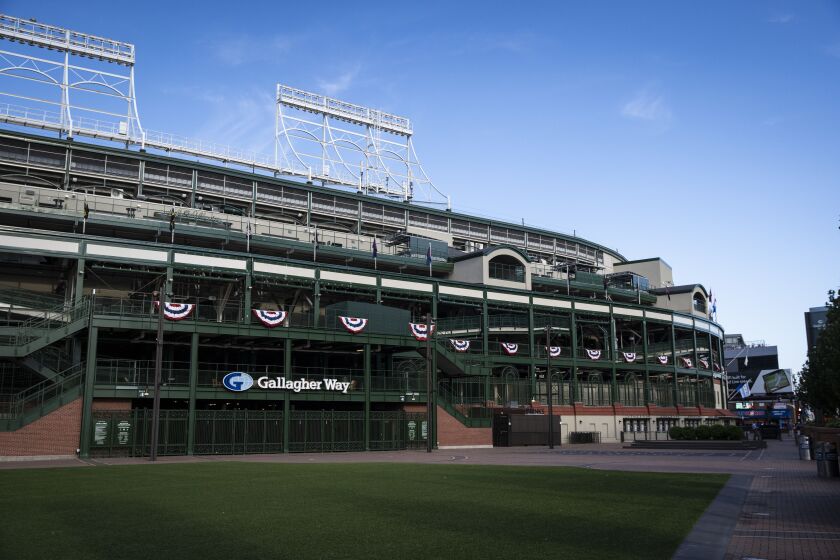 Fans walk by closed gates at Wrigley Field shortly before the start of the opening day game between the Chicago Cubs and the Milwaukee Brewers, Friday evening, July 24, 2020.