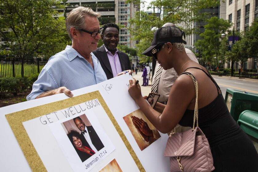 A woman signs a “get well soon” card for Rev. Jesse Jackson, 79, and his wife, Jacqueline, 77, before community activists and faith leaders hold a prayer vigil and news conference outside Northwestern Memorial Hospital, Monday morning, Aug. 23, 2021. The Jacksons were admitted Saturday to Northwestern after testing positive for COVID-19.
